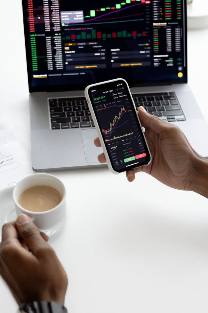 services-02 Person analyzing stock market trends on smartphone with laptop background
